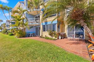 a house with palm trees and a patio at Sandy Straits Poolside Escape with Beach Access in Hervey Bay