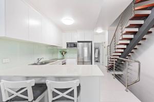 uma cozinha branca com um lavatório e uma escadaria em Little Miss Sunshine - An Oceanside Family Delight em Hervey Bay
