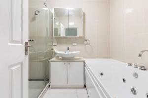 bagno bianco con lavandino e doccia di Little Miss Sunshine - An Oceanside Family Delight a Hervey Bay