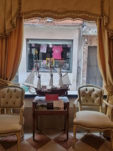 una habitación con 2 sillas y un barco en una ventana en Albergo Casa Peron, en Venecia