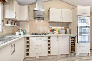 eine Küche mit weißen Schränken und einem Waschbecken in der Unterkunft Artisan Lodge Shorefield Country Park Downton Lymington in Lymington
