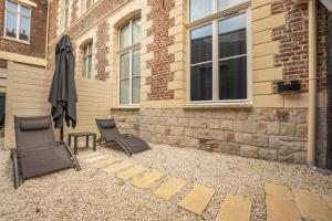 un patio con 2 sillas y una sombrilla junto a un edificio en L'eSPAce détente en Valenciennes