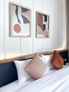 a bed with four pillows and three paintings on the wall at Harmonic HuaHin Pool Villa-3BR, 3 Bath, 2 Kitchen in Hua Hin