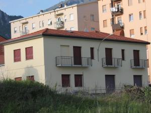 a white building with red shuttered windows and buildings at Grandi Cime Guest House in Lecco