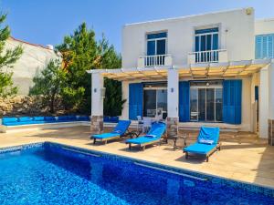 a swimming pool with blue chairs and a house at VILLA NAYA Branch 3 - SANTORINI, Jerash in Rujm al Miḑmār