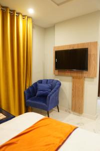 1 dormitorio con silla azul y TV de pantalla plana en Nüva Hotel, en Islamabad