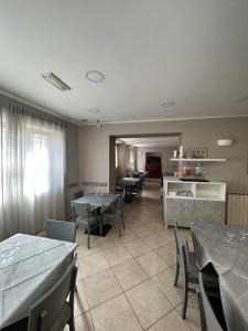 a dining room with tables and chairs and a kitchen at Hotel Le Rose in Tivoli Terme