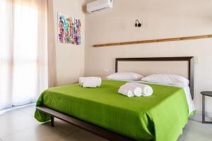 Un dormitorio con una cama verde con toallas. en Borgo del Bambù en Perito