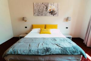 um quarto com uma cama grande e almofadas amarelas em Essenza Hotel em Verrès