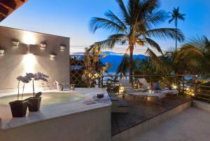 a patio with a hot tub and chairs and palm trees at Abayomi Hotel in Ilhabela