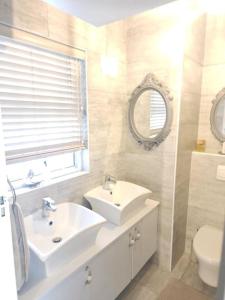 a bathroom with a sink and a toilet and a mirror at Cape Town, Sea Point, Beautiful 2 Bedroom Apartment @Tucked Away in Cape Town