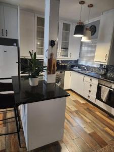 a kitchen with white cabinets and a black counter top at Cape Town, Sea Point, Beautiful 2 Bedroom Apartment @Tucked Away in Cape Town