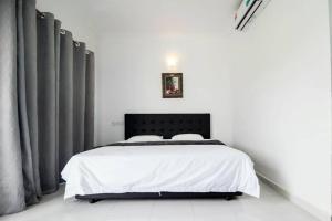 um quarto com uma cama com lençóis brancos e cortinas cinzentas em Langkawi Primrose Seaview em Tanjung Rhu