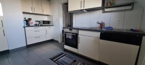 a kitchen with white cabinets and a black stove top oven at Edel Apartments Dulliken in Dulliken