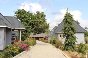 a walkway between two houses with a tree and flowers at Mapeni Lodge in Kidenge