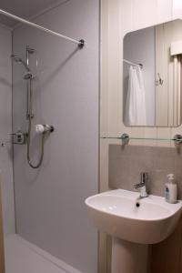 a bathroom with a sink and a shower with a mirror at Smithy Cottage in Strathdon