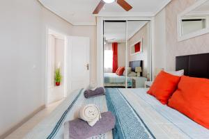 1 dormitorio con 1 cama con almohadas de color naranja y espejo en Modern apartment in Golf del Sur, AC237, tempered pool and ocean view, en San Miguel de Abona 46 fotos más