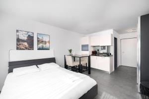 Studio PAOLA Interlaken في إنترلاكن: غرفة نوم بيضاء مع سرير ومطبخ