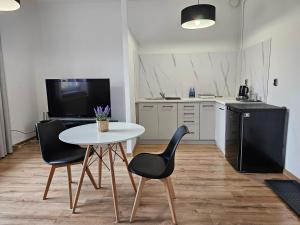 a kitchen with a white table and two black chairs at Apartamenty HARDOM in Opole