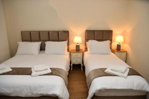 two twin beds in a room with two lamps at NUCA GUESTHOUSE in Metsovo