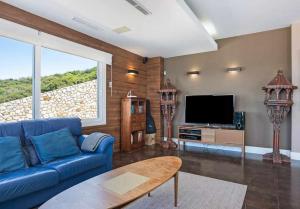 sala de estar con sofá azul y TV en LUJOSAVILLA PISCINA 25 METROS SUIT 60m2 SPA SAUNA, en Zahara de los Atunes