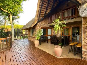 una terraza de madera con una casa con mesa y sillas en Private Villa with Private Pool - Kruger Park Lodge, en Hazyview