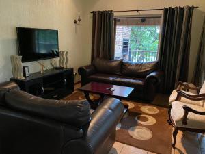 sala de estar con muebles de cuero y TV de pantalla plana en Private Villa with Private Pool - Kruger Park Lodge, en Hazyview