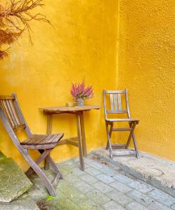 una mesa y una silla junto a una pared amarilla en En lille hel lejlighed i midtbyen - centralt, hyggelig og tæt på alt!, en Randers