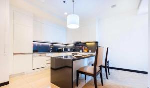 a kitchen with white cabinets and a table and chairs at Luxury Address Res Dubai Marina 1BR a Frank&Frank in Dubai