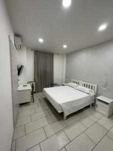 a bedroom with a white bed and a tiled floor at Hotel Le Rose in Tivoli Terme