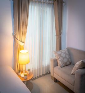 ein Wohnzimmer mit einem Sofa, einer Lampe und einem Fenster in der Unterkunft Cozy room only 20 minutes from the city center! in Ngaglik