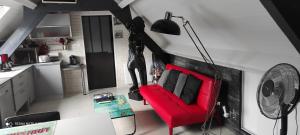 uma sala de estar com uma cadeira vermelha e um candeeiro em La louisiane em Montivilliers