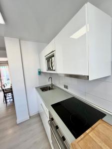 una cocina con armarios blancos y fregadero en Apartamento de playa reformado, en Rincón de la Victoria