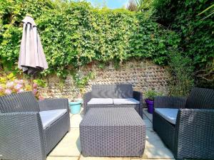 a patio with two wicker chairs and an umbrella at Central Location with Garden in Seaford