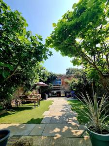 a garden with a pathway and tables and trees at Central Location with Garden in Seaford