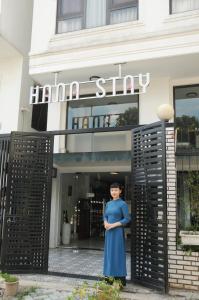 Una donna con un vestito blu in piedi davanti a un palazzo di Hana Stay Trần Quốc Hoàn a Hanoi