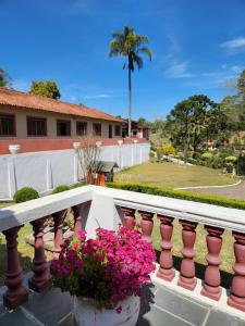 un balcón con flores rosas y una palmera en Pousada Pedacinho do Ceu suite Giulia 4, en Cunha