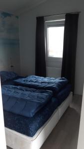 a bedroom with a bed with blue sheets and a window at CS 34 - Vakantiepark Callassande in Callantsoog