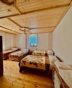 Peshkopi的住宿－Bujtina Oxhaku i Docit，客房设有三张床和木制天花板。