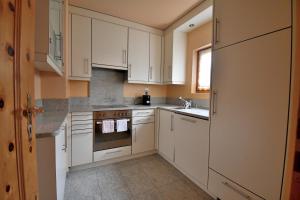 a kitchen with white cabinets and a sink at 3.5 Dmura Fewo Bernina in Samedan