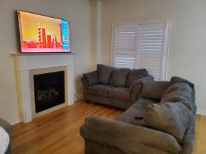 RAESABU GUEST HOUSE في برامبتون: غرفة معيشة بها أريكة وتلفزيون فوق موقد