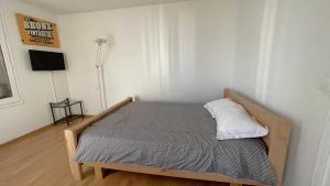 1 dormitorio con cama de madera y TV. en Les Aubépines entre Disney et Paris, en Champs-Sur-Marne