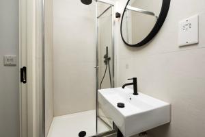 een witte badkamer met een wastafel en een spiegel bij Modern City Living Studios at Antigallican in Londen