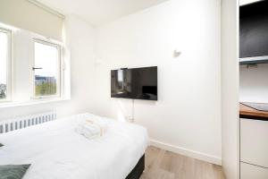 a white bedroom with a bed and a flat screen tv at Modern City Living Studios at Antigallican in London