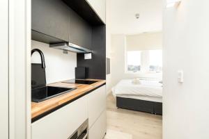 een keuken met een wastafel en een bed in een kamer bij Modern City Living Studios at Antigallican in Londen