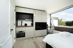 een slaapkamer met witte kasten en een groot raam bij Modern City Living Studios at Antigallican in Londen