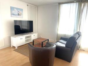 ein Wohnzimmer mit einem Sofa und einem Flachbild-TV in der Unterkunft Les Aubépines entre Disney et Paris in Champs-Sur-Marne