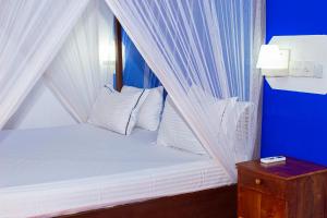 uma cama com lençóis brancos e almofadas num quarto em Surasa Beach Resort em Weligama