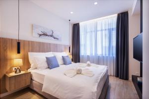 um quarto com uma grande cama branca com almofadas azuis em Hestia - Romvis 9 em Atenas