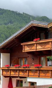 a wooden house with red flowers on a balcony at HAUS ERIKA apartments in Sölden